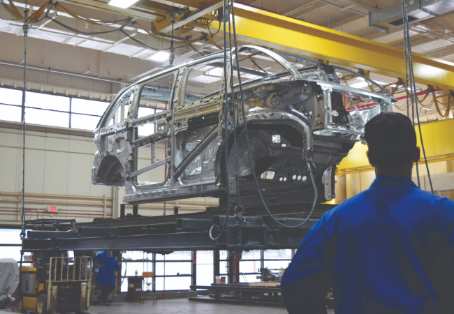 Silver metal car chassis hung in a production environment