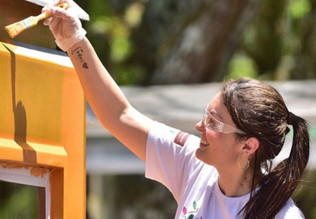 PPG volunteer revitalizing school exterior by painting with safety glasses