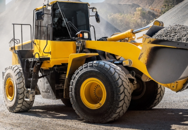 Yellow and black digger moving dirt in a quarry environment