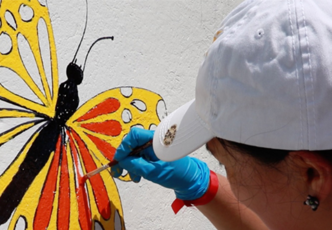 Woman painting butterfly on wall in Medellin, Colombia 