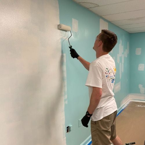 guy painting wall white 