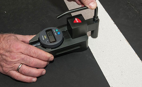 Worker measuring thickness of markings