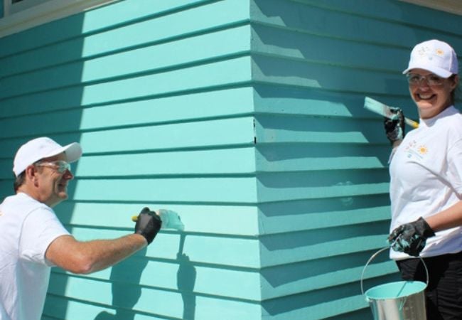 colorful communities' volunteers painting exterior wall teal in Auckland, New Zealand