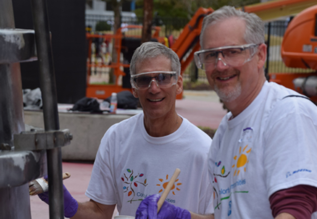 two men painting a metal pipe