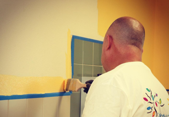 Man painting bathroom wall yellow