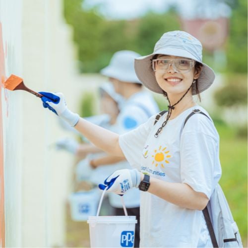 volunteer painting wall with PPG bucket