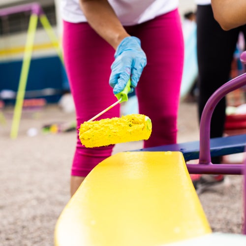 volunteer painting playground equipment yellow 