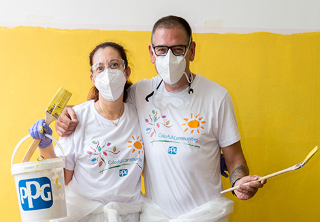 two people painting wall yellow 