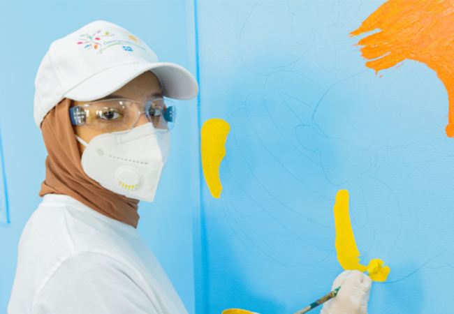 girl painting mural on wall