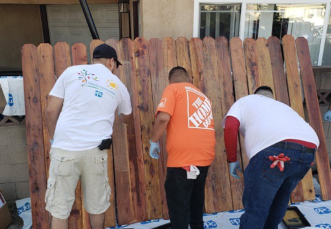 men staining fence