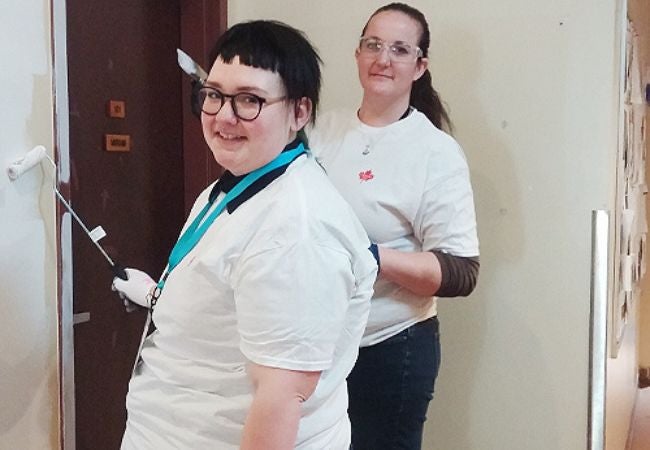 two women painting interior.