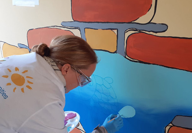 Girl painting mural of fish on the wall 