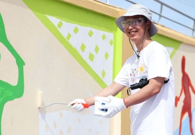 volunteer painting a mural