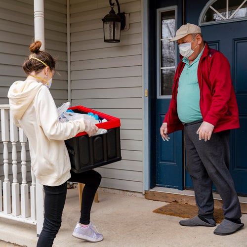 woman delivering covid emergency supplies to older man 