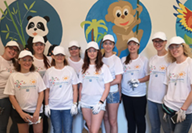 Volunteers standing in front of a mural 