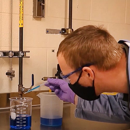 Ed Hellerman measuring blue liquid in beaker for National Chemistry Week 