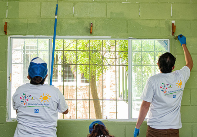 Volunteers painting a wall green in El Salvador 