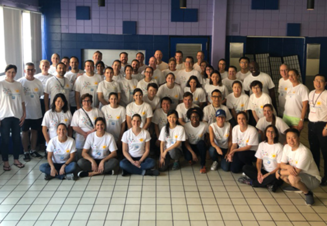 large group of volunteers in front of purple wall