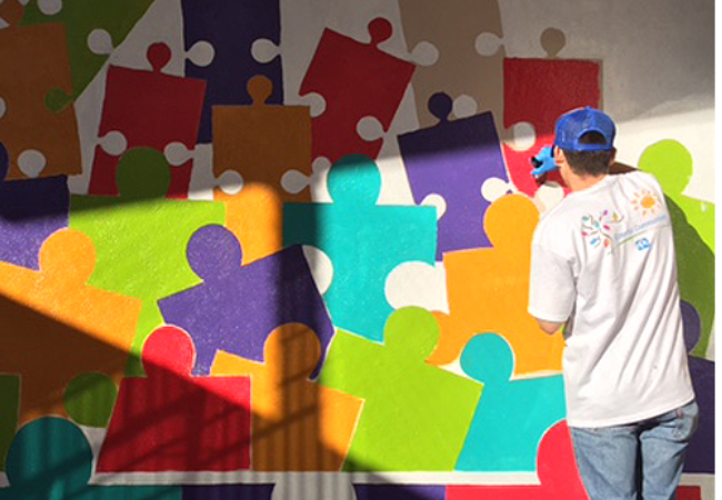 Man painting puzzle piece mural in Hermosillo Mexico 