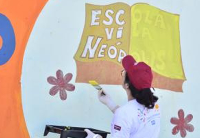 Woman painting a wall mural of a book