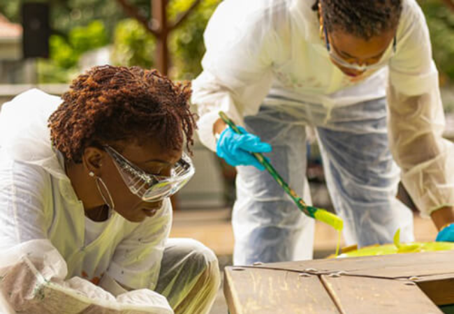 Two volunteers painting bench yellow in Guadeloupe, French Overseas