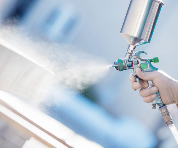 Spray gun spraying liquid coatings from a gloved hand