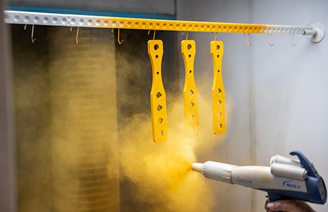 Spraying PPG sustainable yellow coating onto parts in a spray booth