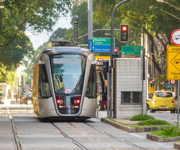 A stationery tram at a tram stop waiting for a red traffic light to change