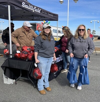 Crystal Gray, human resources coordinator, Smithfield Foods, and Toni King, environmental resource specialist, Smithfield Foods, load cars with Smithfield Hickory Smoked Spiral Sliced Hams and holiday side items donated by Food Lion in Kenansville, North Carolina.