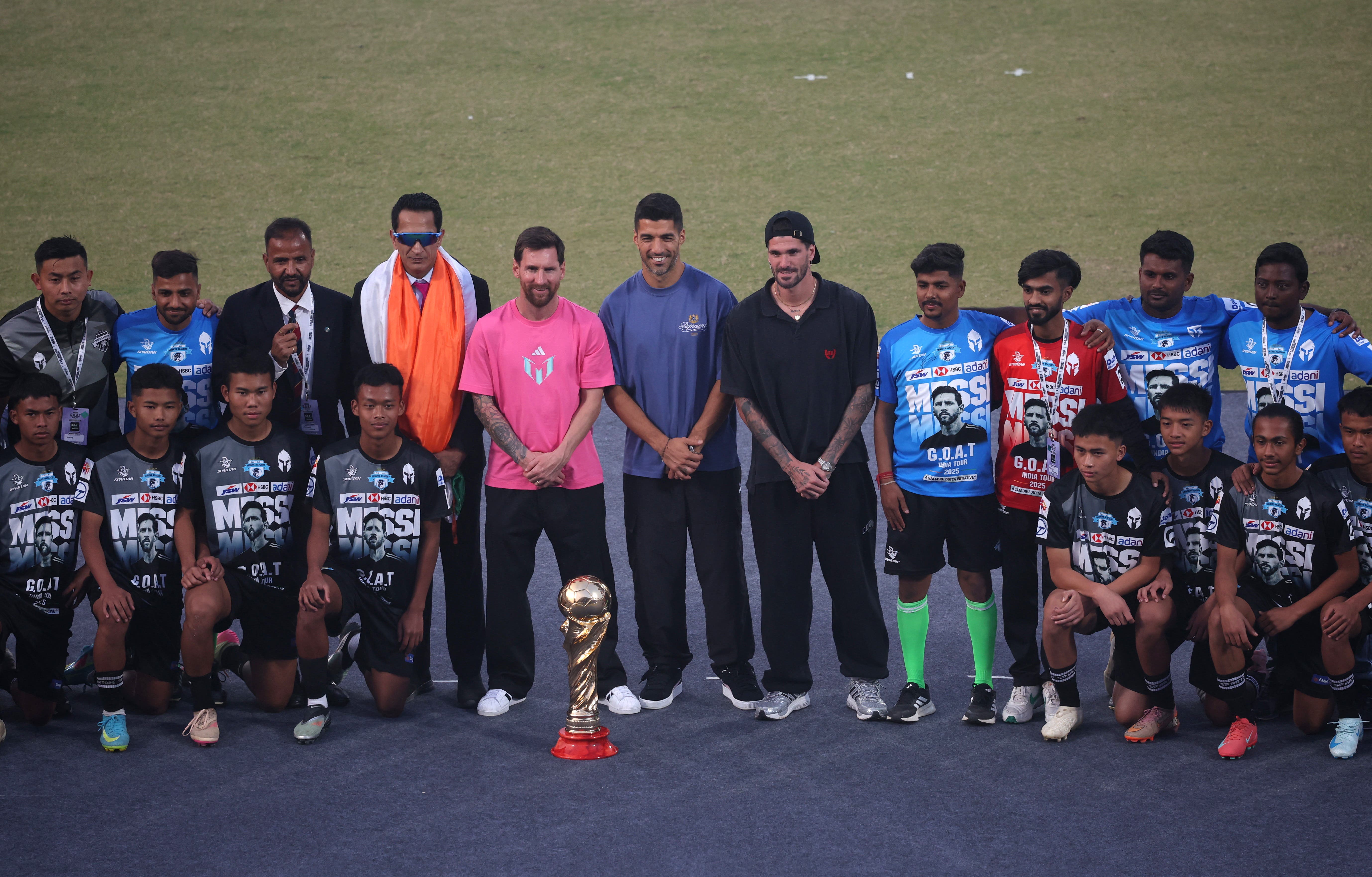 Soccer Football - Lionel Messi Tour of India - Arun Jaitley Stadium, New Delhi, India - December 15, 2025 Argentina and Inter Miami's Lionel Messi with his Inter Miami teammates Rodrigo De Paul and Luis Suarez pose with a replica world cup trophy at the stadium during his tour of India REUTERS/Adnan Abidi