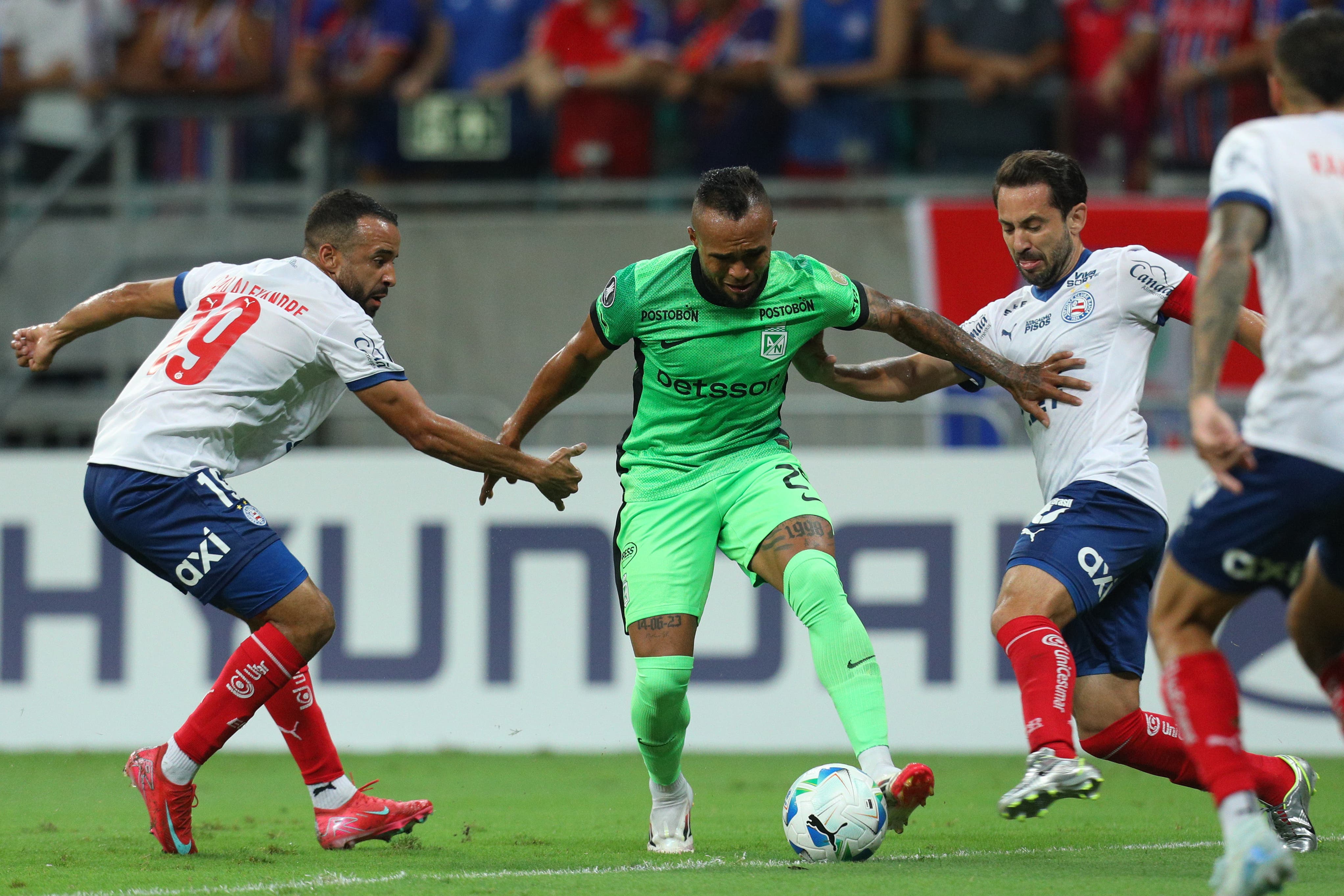Caio Alexandre (i) de Bahia disputa el balón con Andrés de Jesús Sarmiento (c) de Atlético Nacional este jueves, en un partido de la fase de grupos de la Copa Libertadores entre Bahia y Atlético Nacional, en el estadio