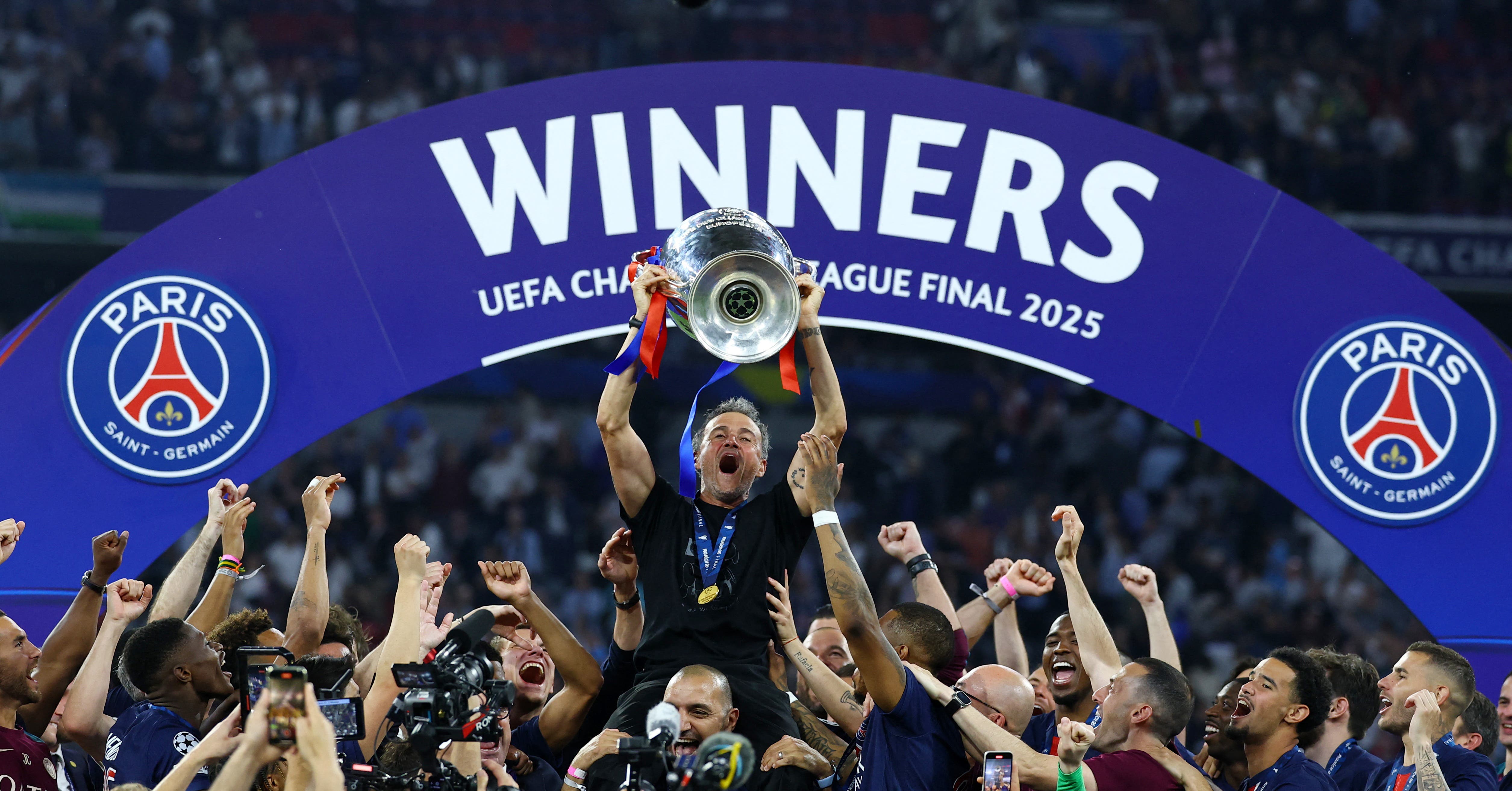Paris St Germain coach Luis Enrique lifts the trophy as he celebrates with his players after winning the Champions League 