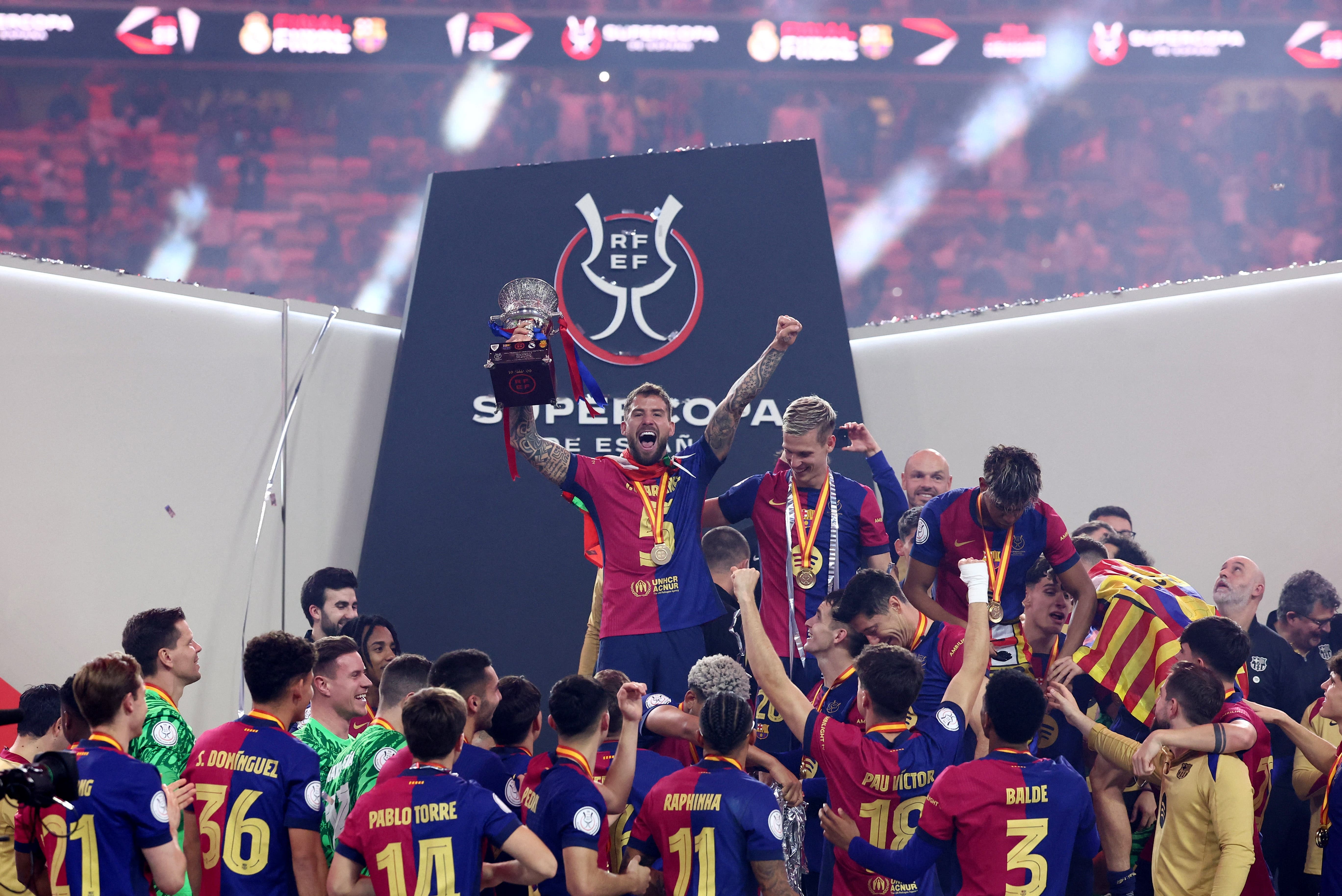 FC Barcelona's Inigo Martinez celebrate with the trophy and teammates after winning the Spanish Super Cup