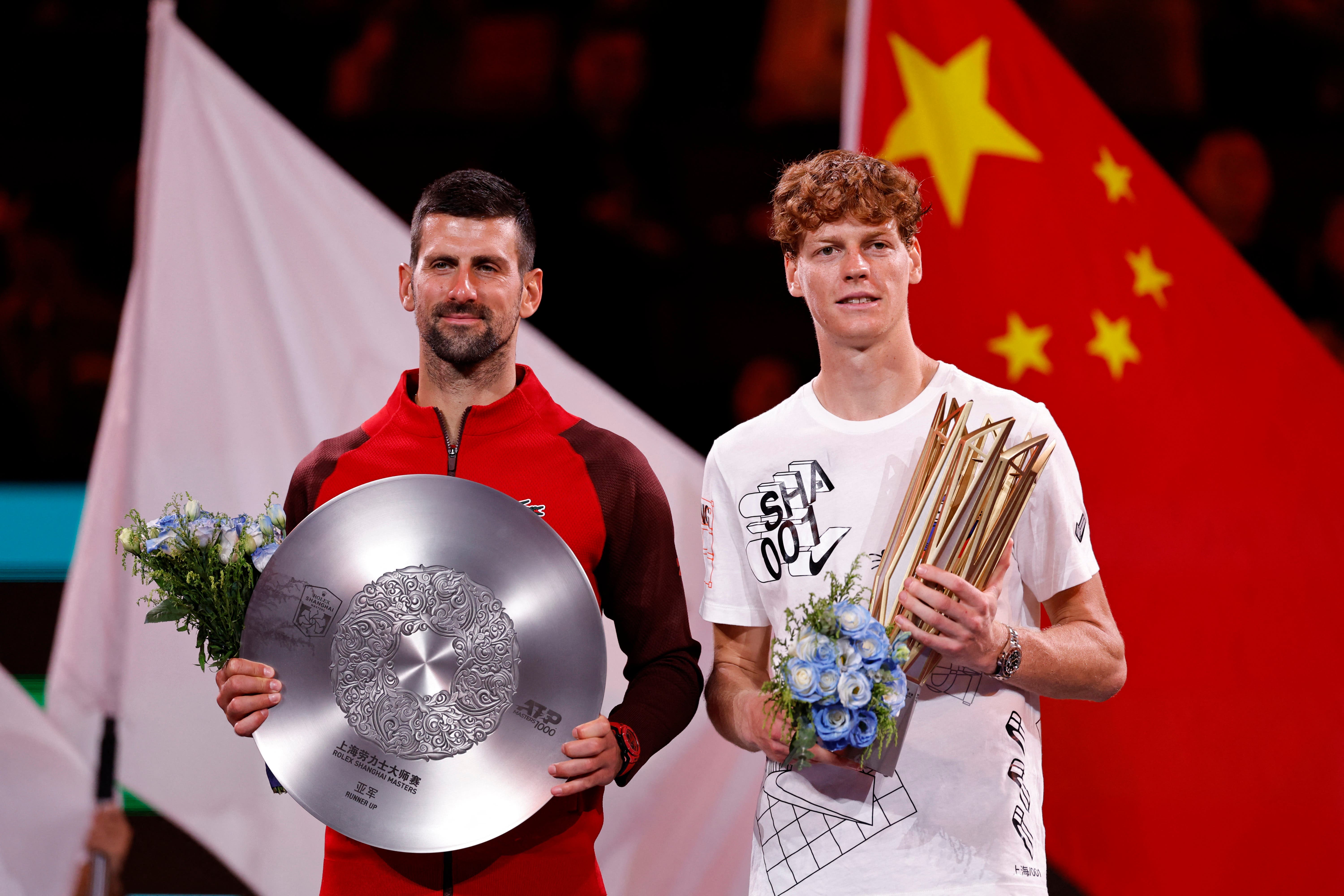 Italy's Jannik Sinner celebrates with the trophy after winning his final match as Serbia's Novak Djokovic poses with the runners up trophy