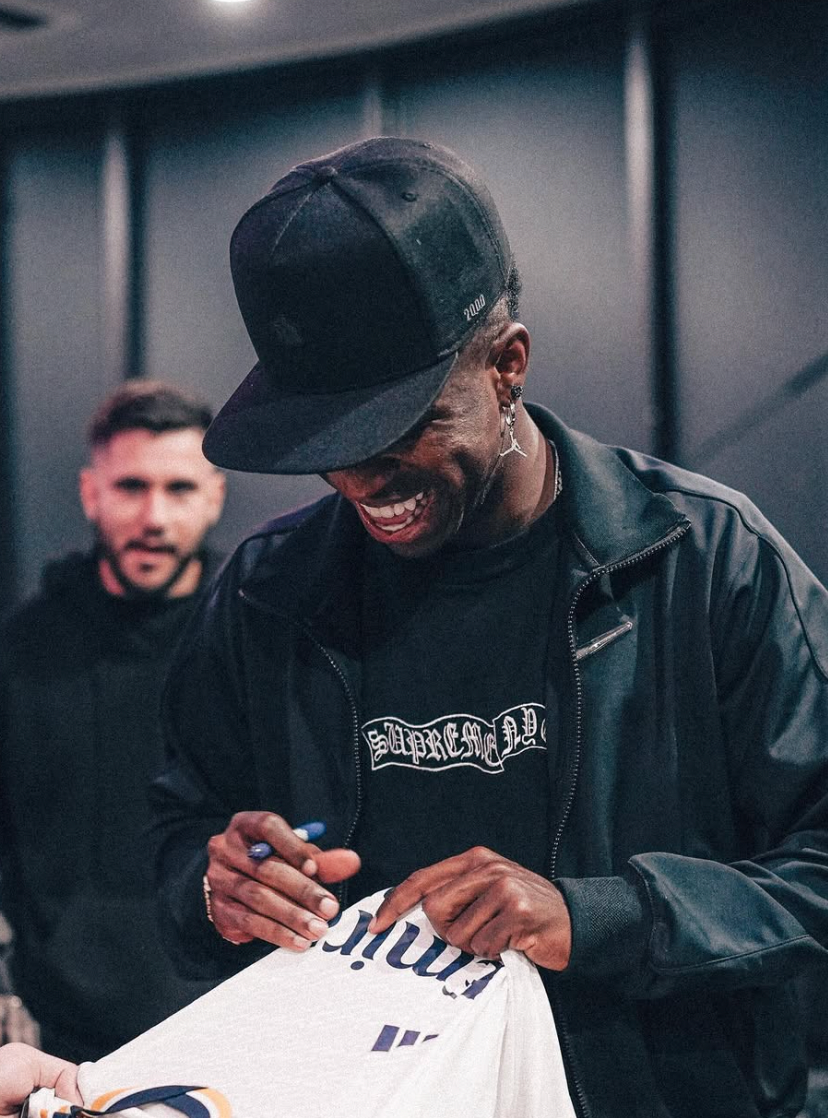 Vinicius firmando una playera del Real Madrid