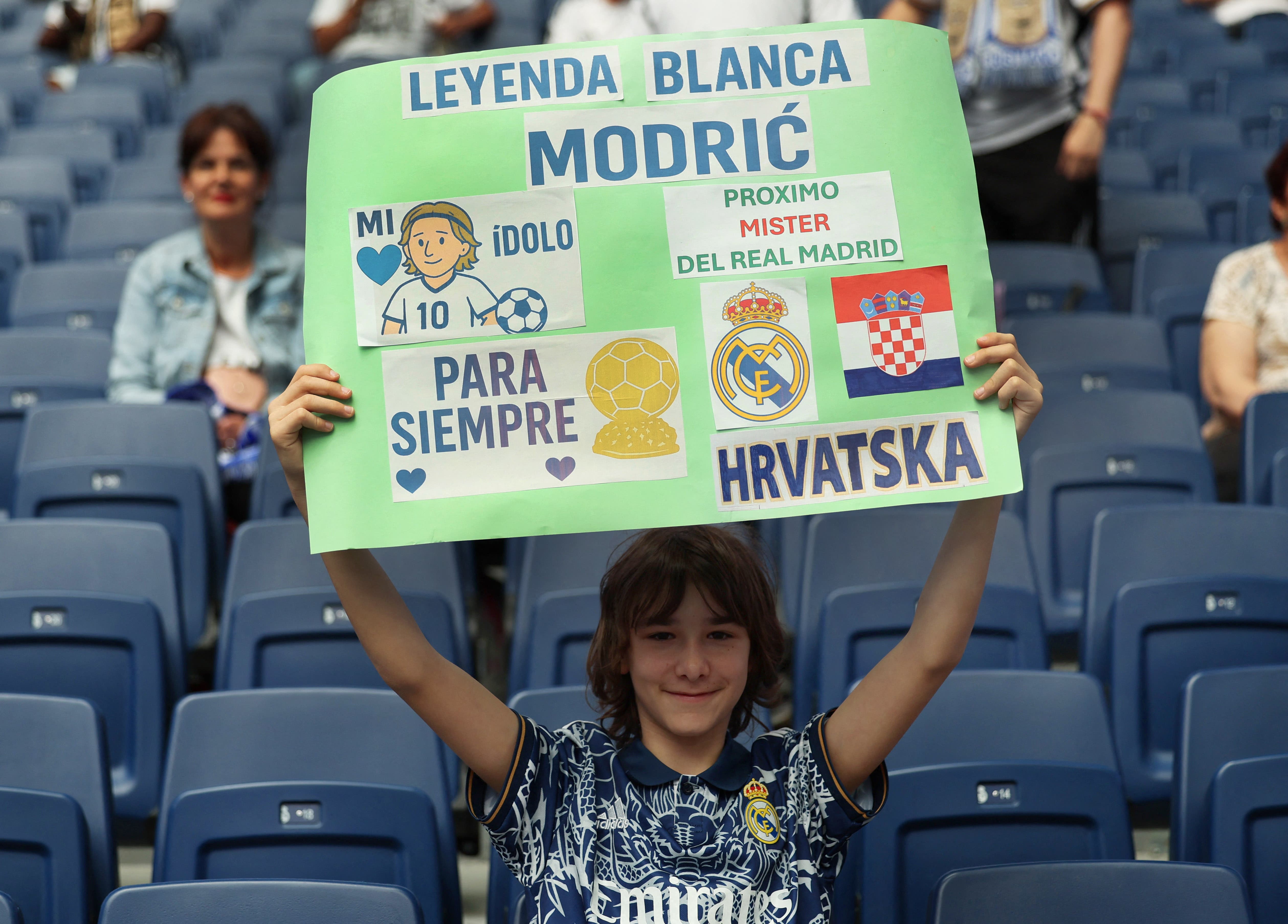 A young Real Madrid fan in the stands holds a banner for Luka Modric before the match 