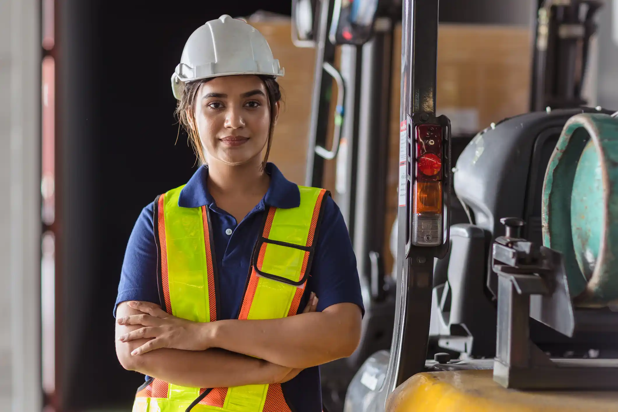 Female engineering apprentice in high vis jacket and protective gear, stood at a factory