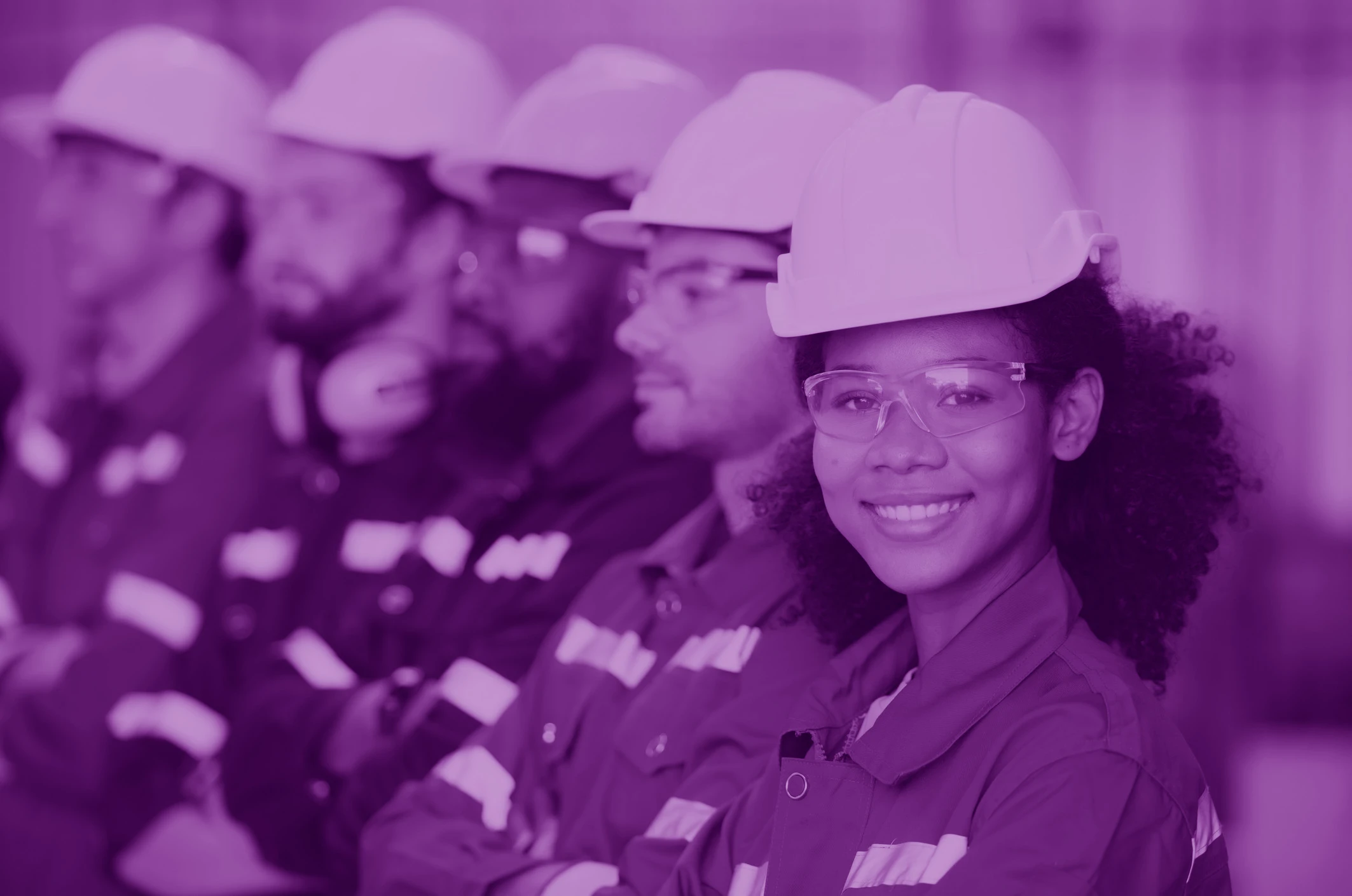 Row of engineers with hard hats with one smiling at the camera