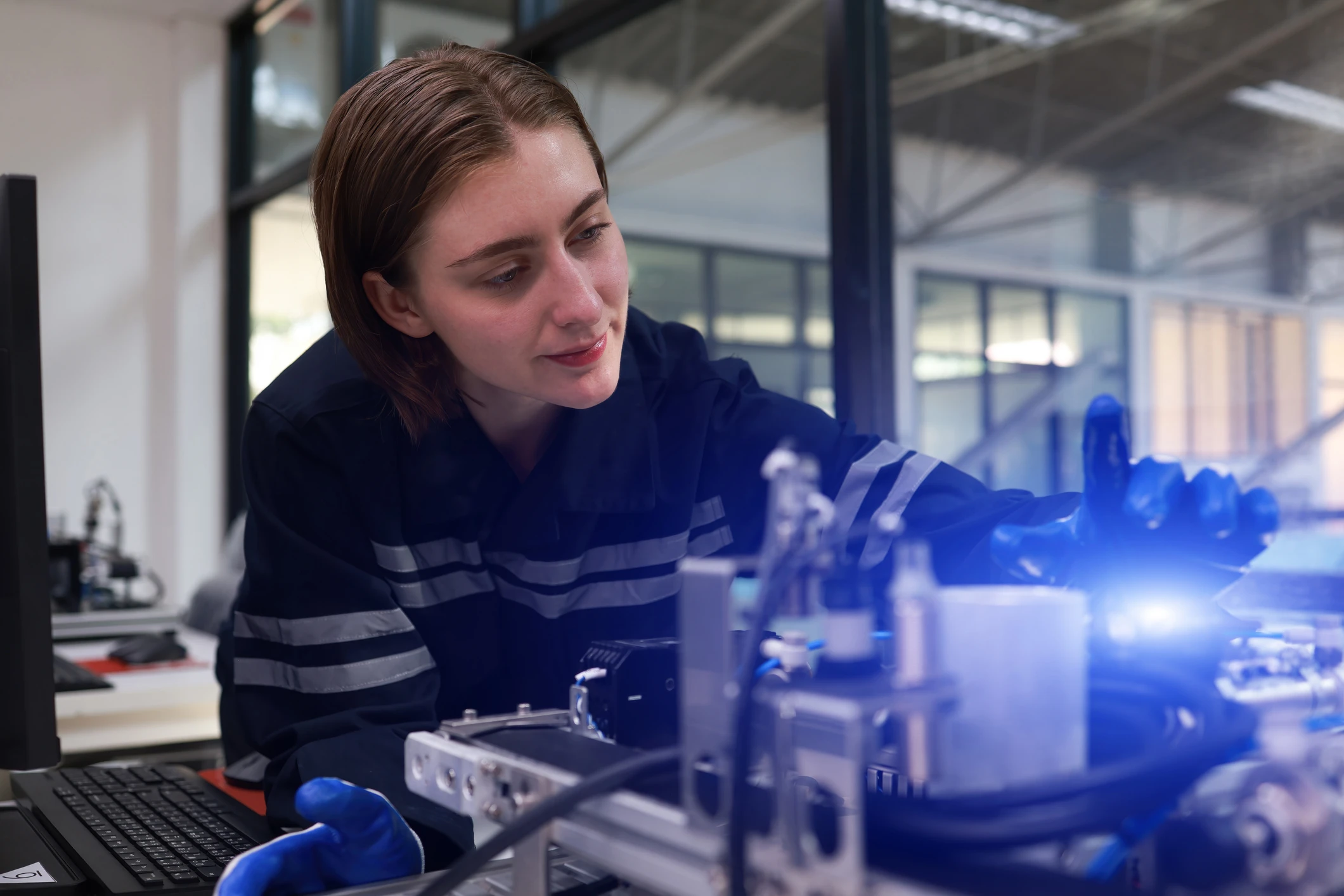 Woman wearing uniform working on a machine in engineering lab