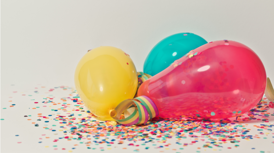 photo of pink, yellow and blue balloons and confetti