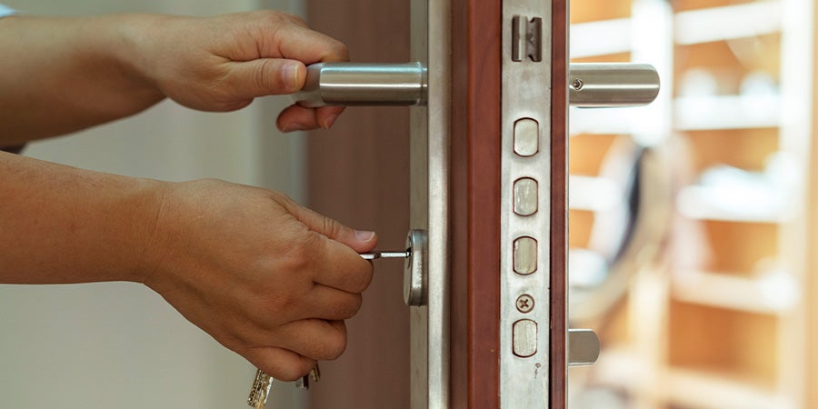 Hands on door handle and key in lock