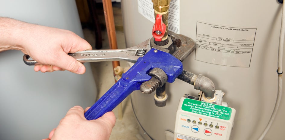 person using two wrenches on boiler