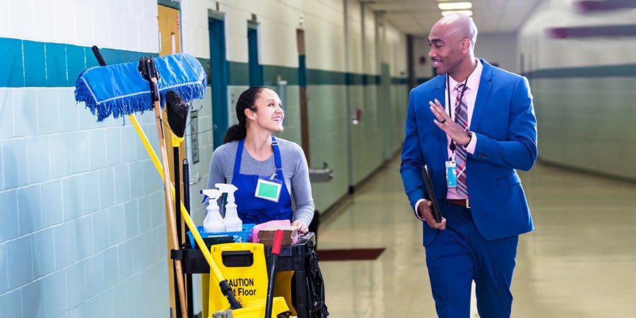 School principal and janitor visiting in hallway