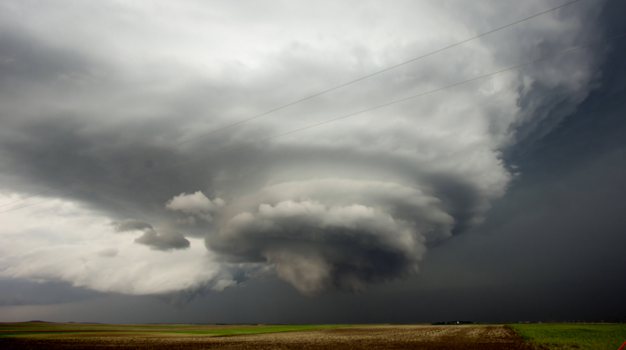 photo of a large tornado cloud touching down on open land