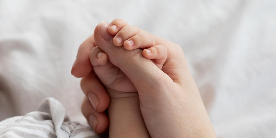 Adult hand holding a baby's hand