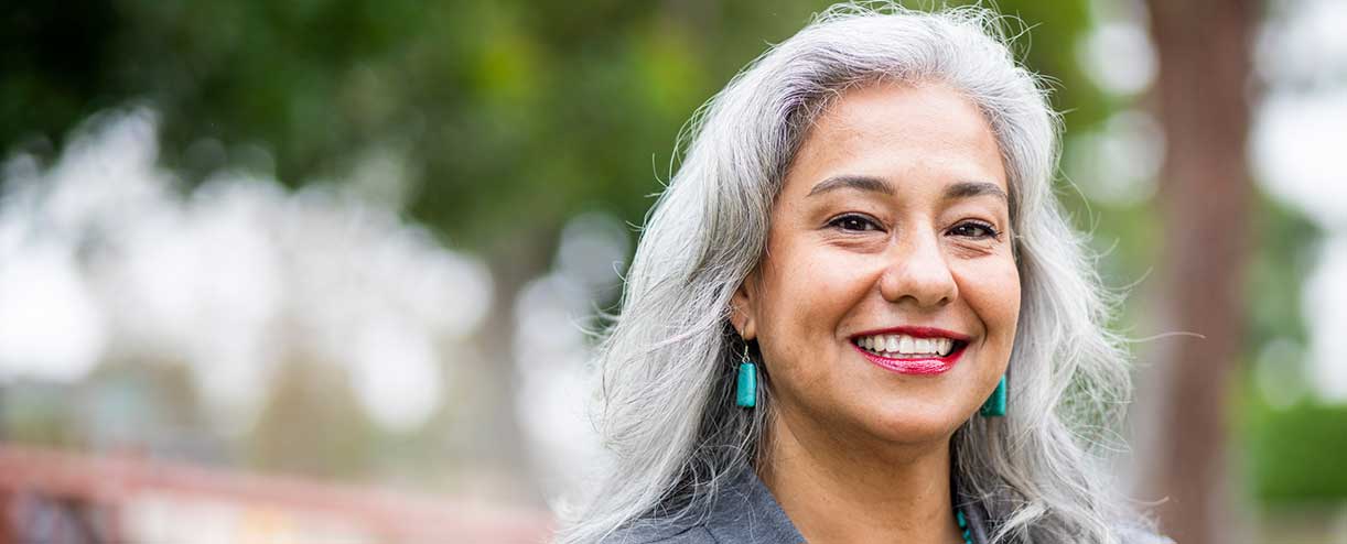 A woman with gray hair smiles happily.