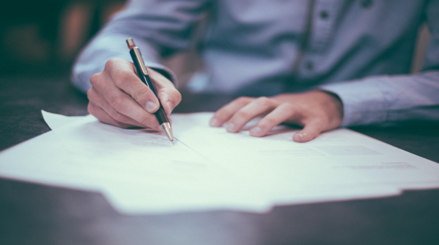 photo of a man signing documents with a pen