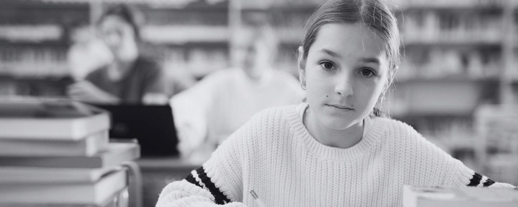 Middle school student, girl, in sitting in library, staring directly at camera, serious
