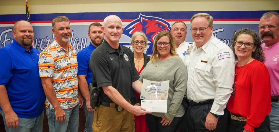 TASB Risk Management Marketing Representative Heide Gaden presents a Fund Excellence Award to Bullard ISD Officer Clayton Bryant and district board members (left-right) Jason Stainback, President Cory Zahirniak, Chris McNertney, Secretary Stephanie Luper, Vice President Brian Vestal, Susie Saxion, and Jason Campbell. Also on hand was Shawn Salter (long-sleeve, white shirt) of Christus Health.