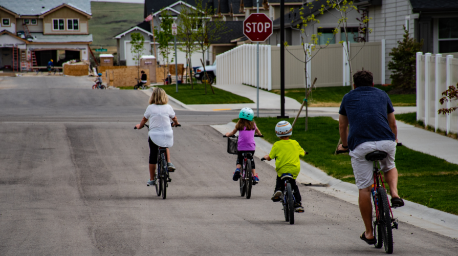 photo of a family of four riding bicycles through a neighborhood
